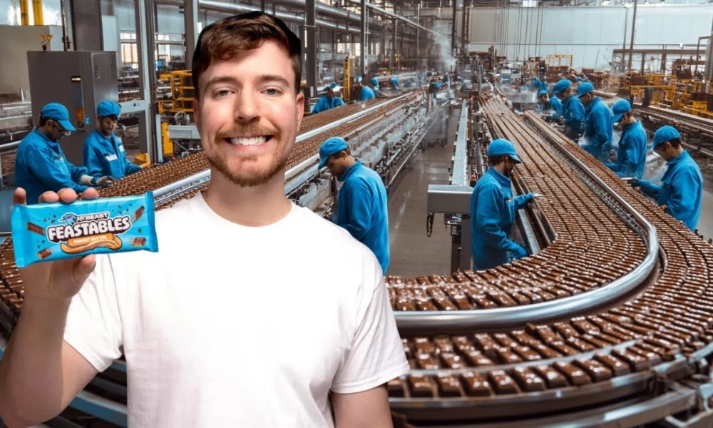 | Feastables: MrBeast's $250M Chocolate Empire & Why It's More Profitable Than YouTube MrBeast holding a chocolate bar inside a high volume Feastables automated confectionery factory assembly line