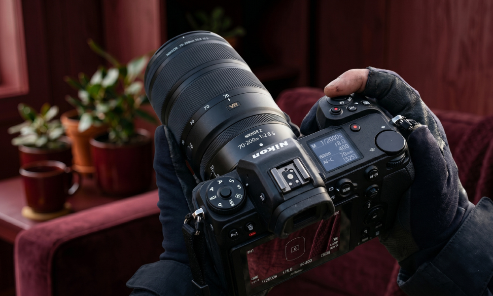| Canon vs Nikon vs Sony: Best Camera Brand for Beginners & Pros (2026) Close up view of an industrial Nikon mirrorless digital camera body attached to a Nikkor Z telephoto zoom lens