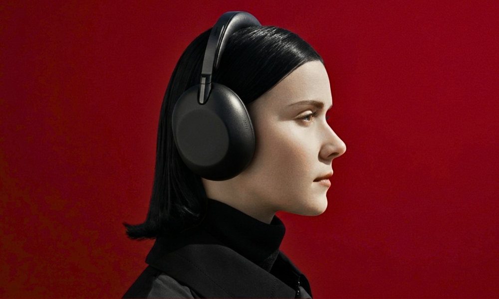 | Bose vs Sony Headphones: Which Is Better in 2026? Side profile view of a user wearing the Sony WH-1000XM6 active noise cancelling headphones over a solid red backdrop