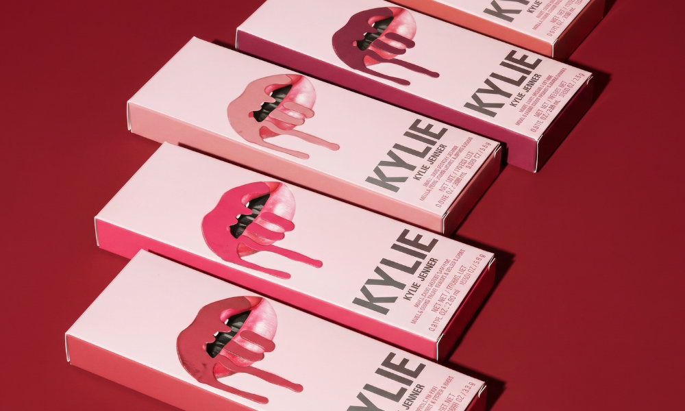 | Kylie Cosmetics Lip Kit Review 2026: Is It Still Worth Buying? Four pink Kylie Jenner lip kit packaging boxes arranged diagonally showing the iconic dripping liquid lips logo art