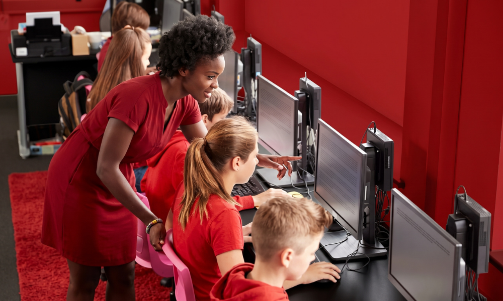 | How Pear Assessment Is Transforming Digital Education Testing An educator in a red dress guiding a student through a screen based test format on a classroom terminal line
