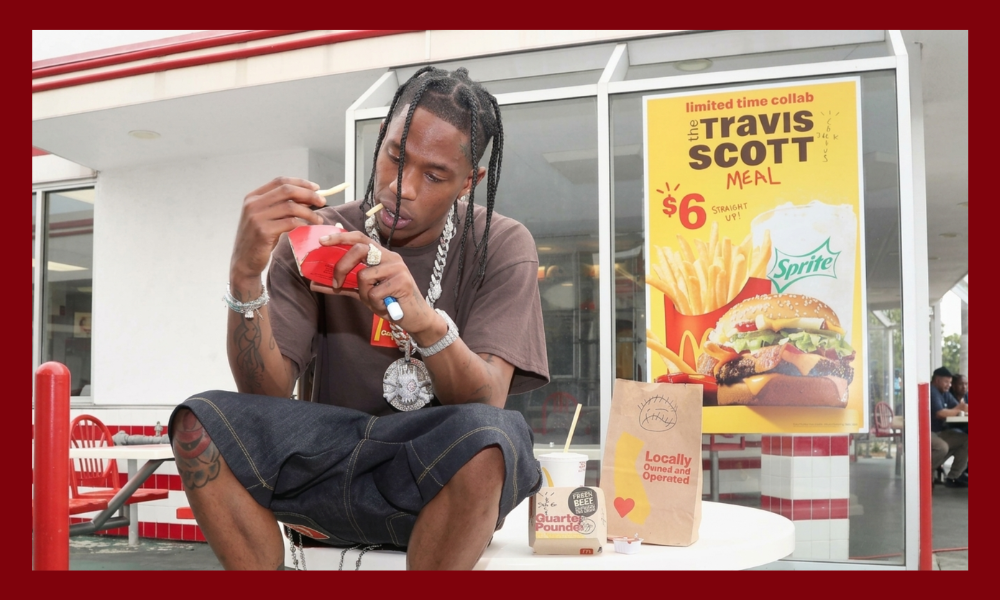 | McDonald's vs. Burger King: Whose Social Media Strategy Actually Works? Rapper Travis Scott eating french fries outside a retail store window displaying the Travis Scott Meal poster