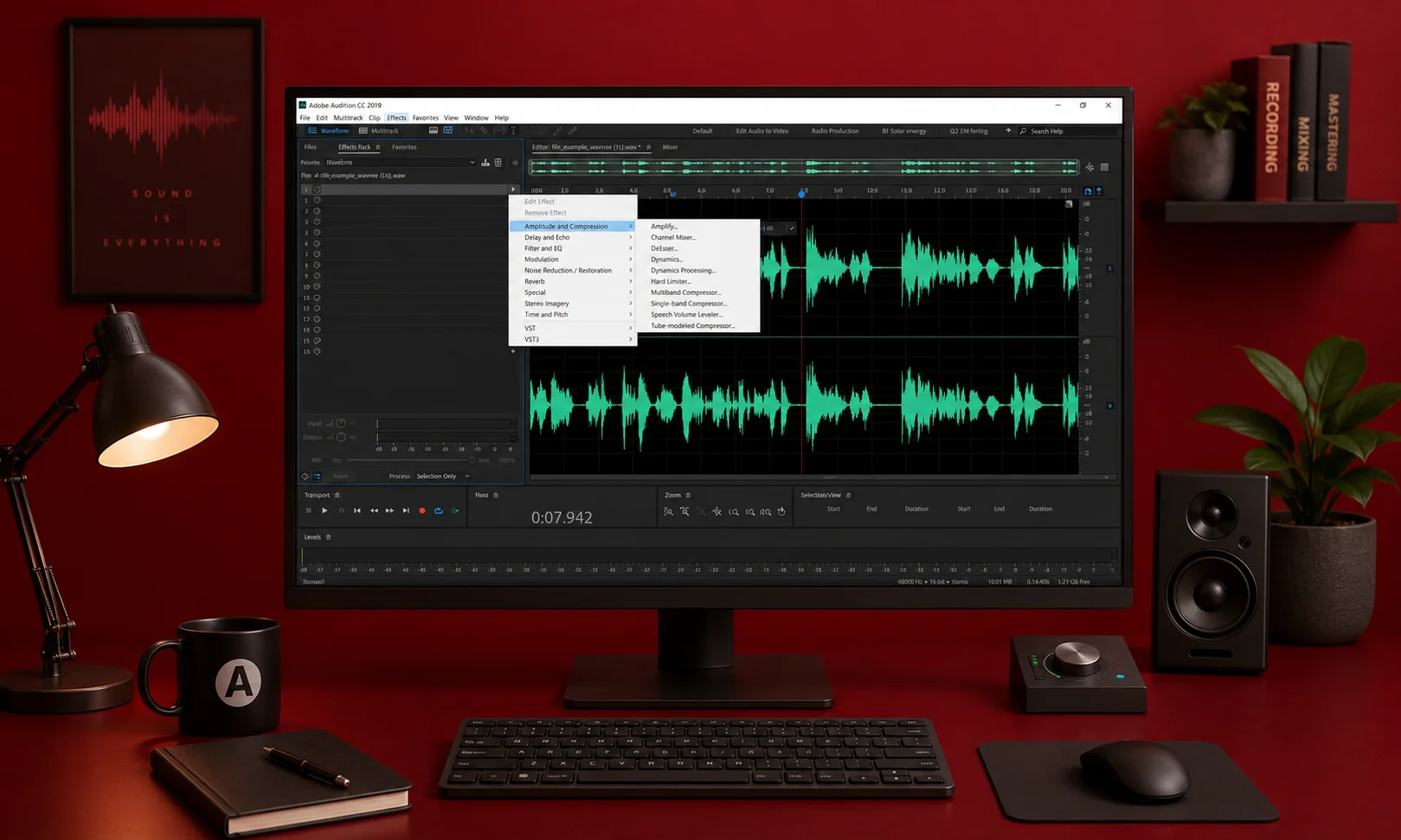 A desktop monitor displaying Adobe Audition waveforms in a red-lit studio environment