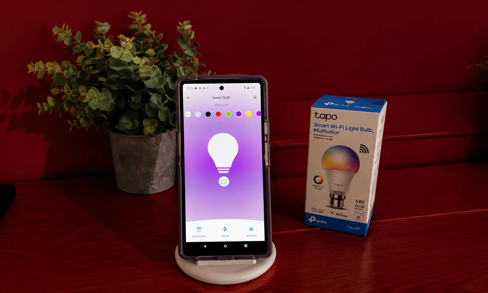 Tapo smart bulb on stand with product box in red room