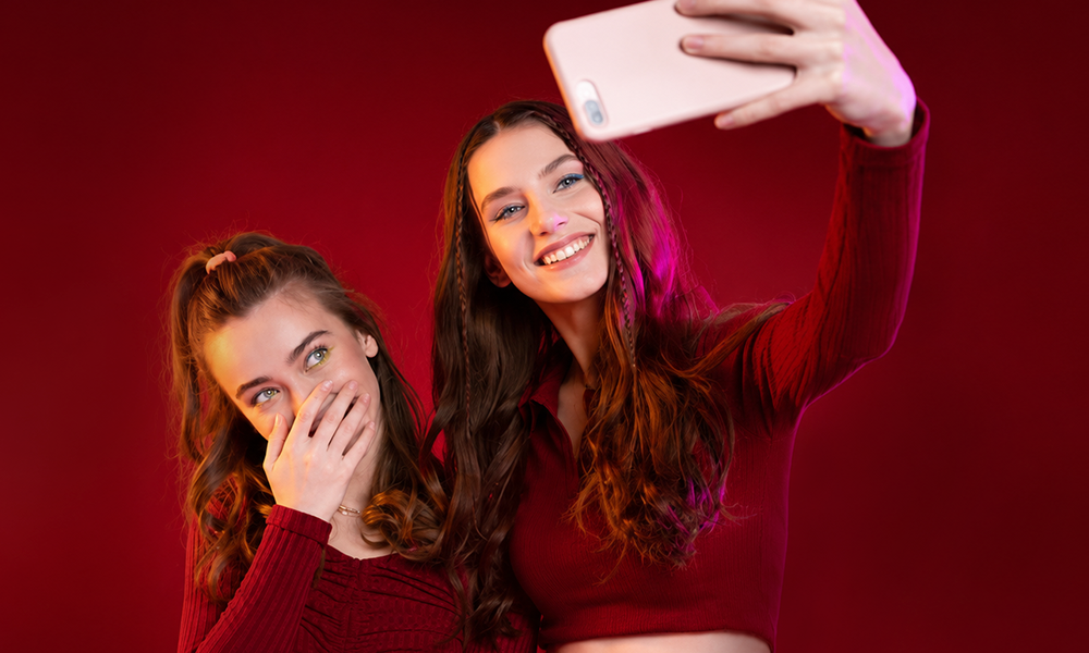 Two smiling women in red outfits taking a selfie indoors