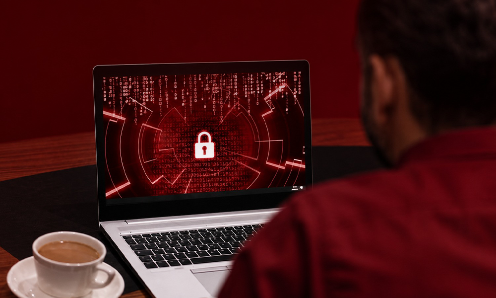 | 6 Lesser-Known Tech Brands Crushing It in Cybersecurity Person working on a laptop with a digital lock icon for cybersecurity