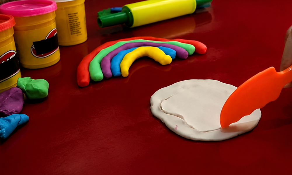 Clay sculpting process with tools on a deep red background by Brand ClickX.
