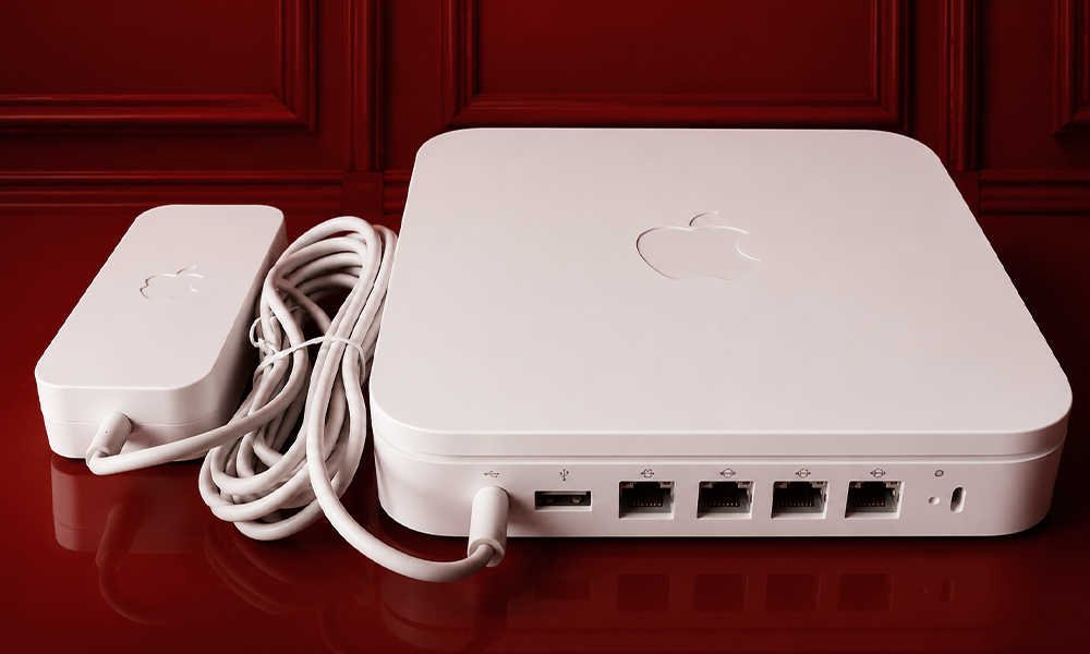 | 5 Tech Companies That Killed Iconic Products Prematurely White Apple AirPort Time Capsule router with power cable on red surface.