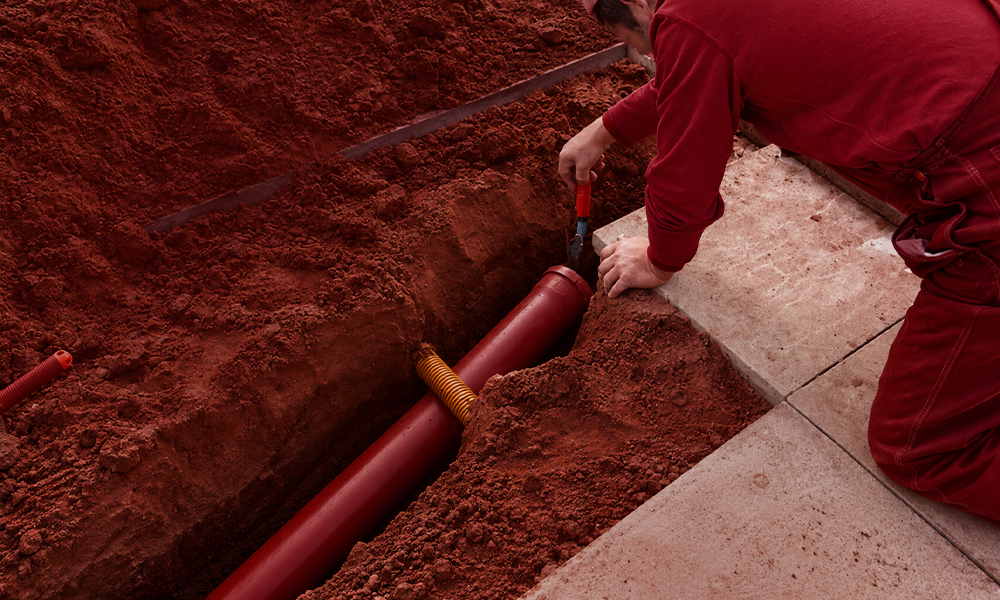A technician working on a pipe inside a trench.