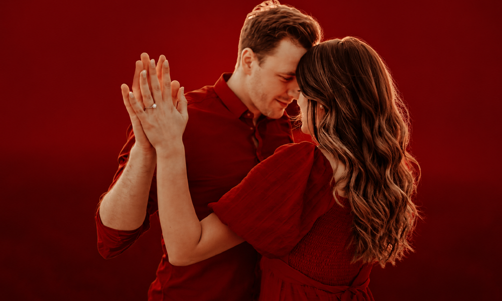 A couple dancing together in an intimate, red-themed setting.