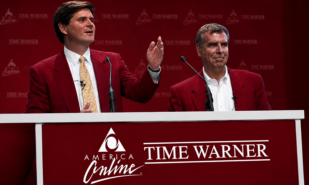 Two speakers presenting at a corporate panel discussion.