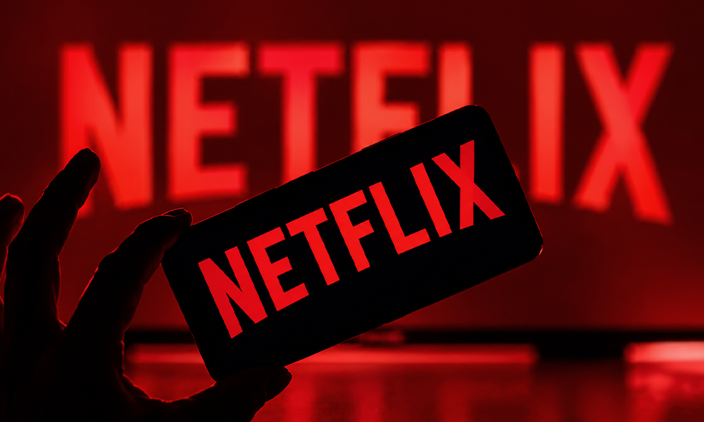 | 5 Tech Companies That Killed Iconic Products Prematurely Hand holding a smartphone displaying the Netflix app logo in red.