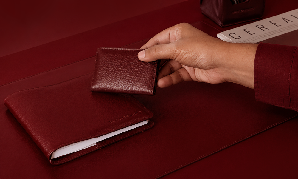 hand placing a small leather wallet onto a flat surface.