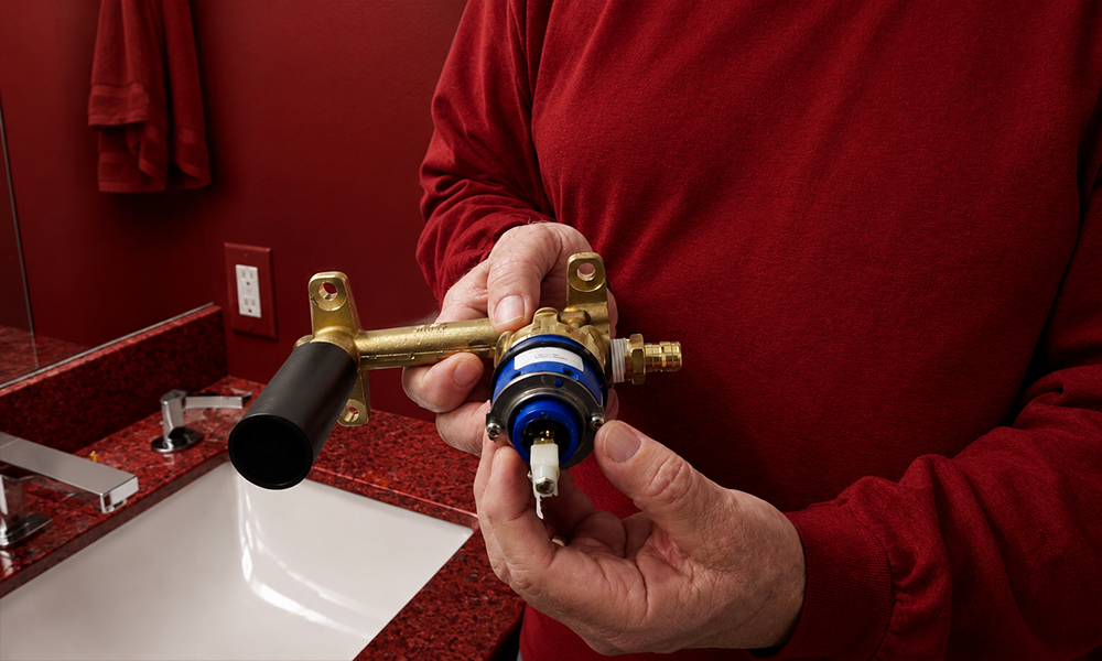 Hands assembling parts of a plumbing fixture in a kitchen setting.