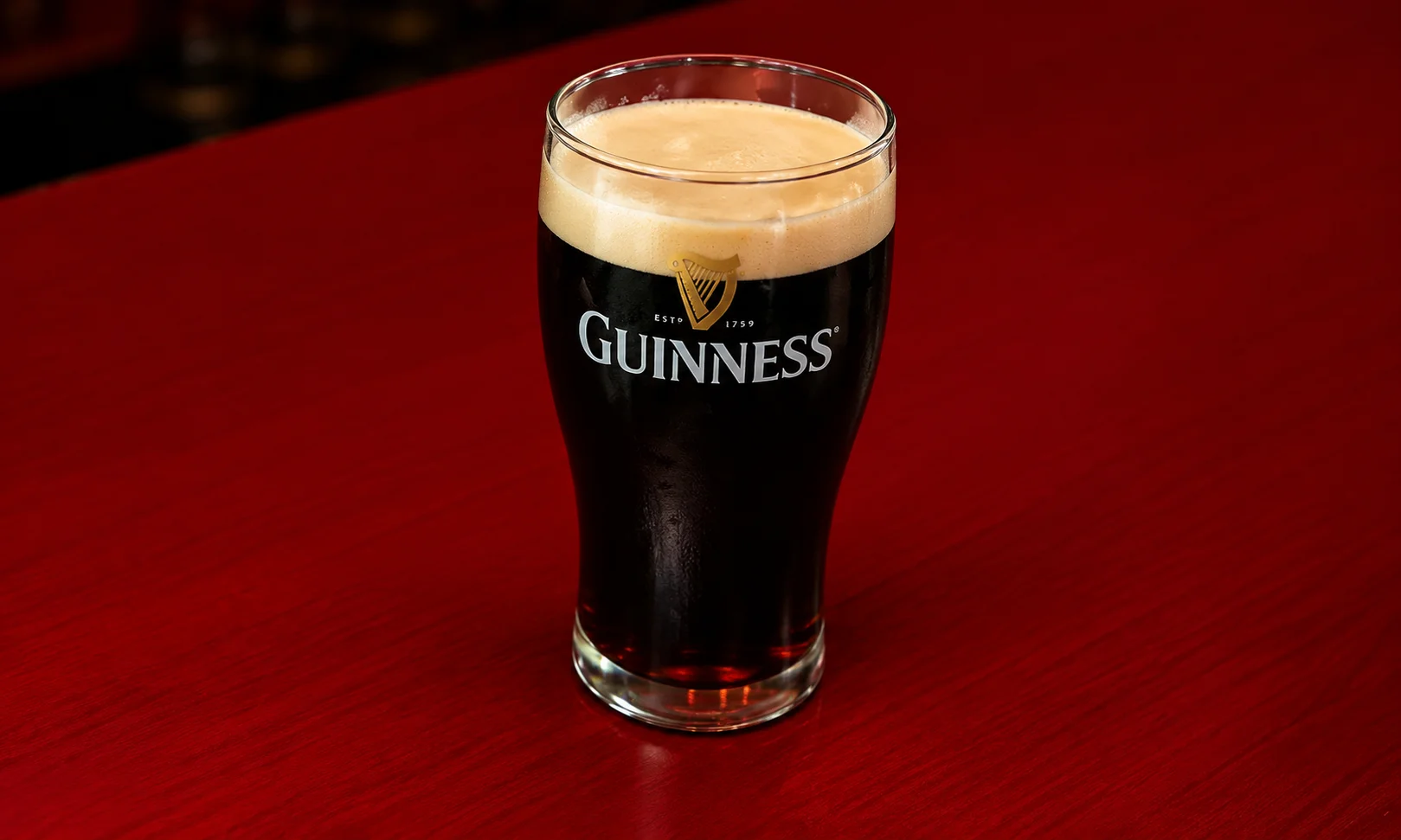 | The Top Brand Campaigns of 2026: The Ones That Actually Worked A glass of Guinness sitting on a beer mat under red ambient lighting