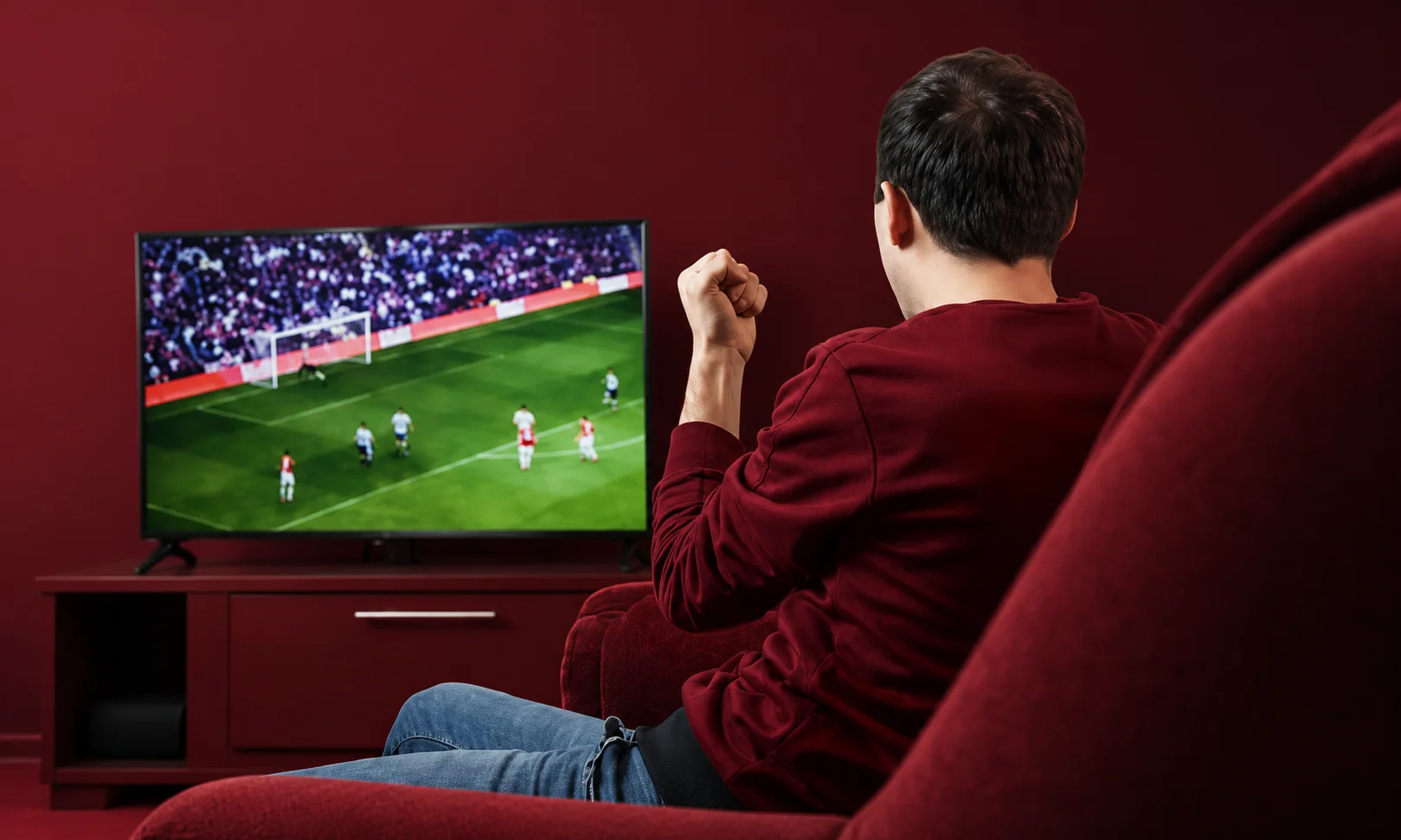 Person watching a live match on TV in a red room