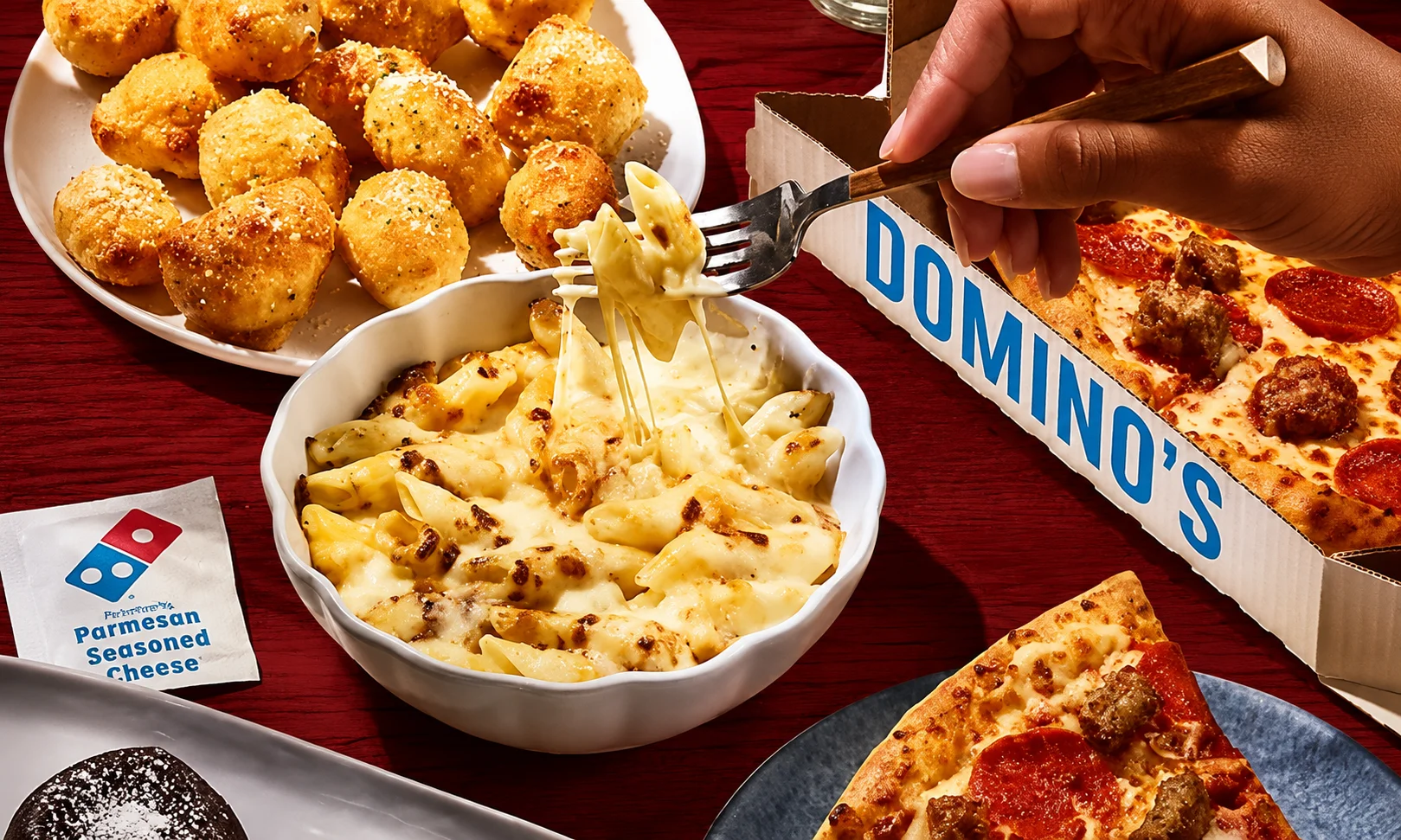 | Domino's Pizza: Menu, Deals & Order Online 2026 A bowl of baked pasta and sides arranged on a red-lit dining surface
