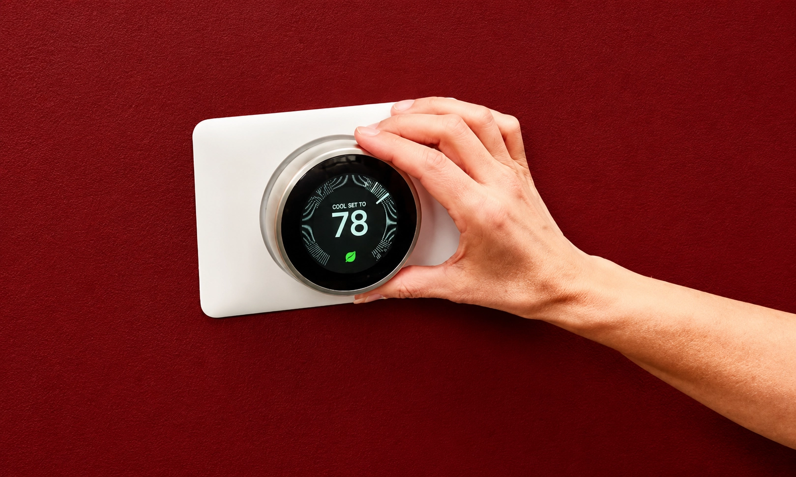 A hand interacting with a modern wall-mounted smart thermostat.