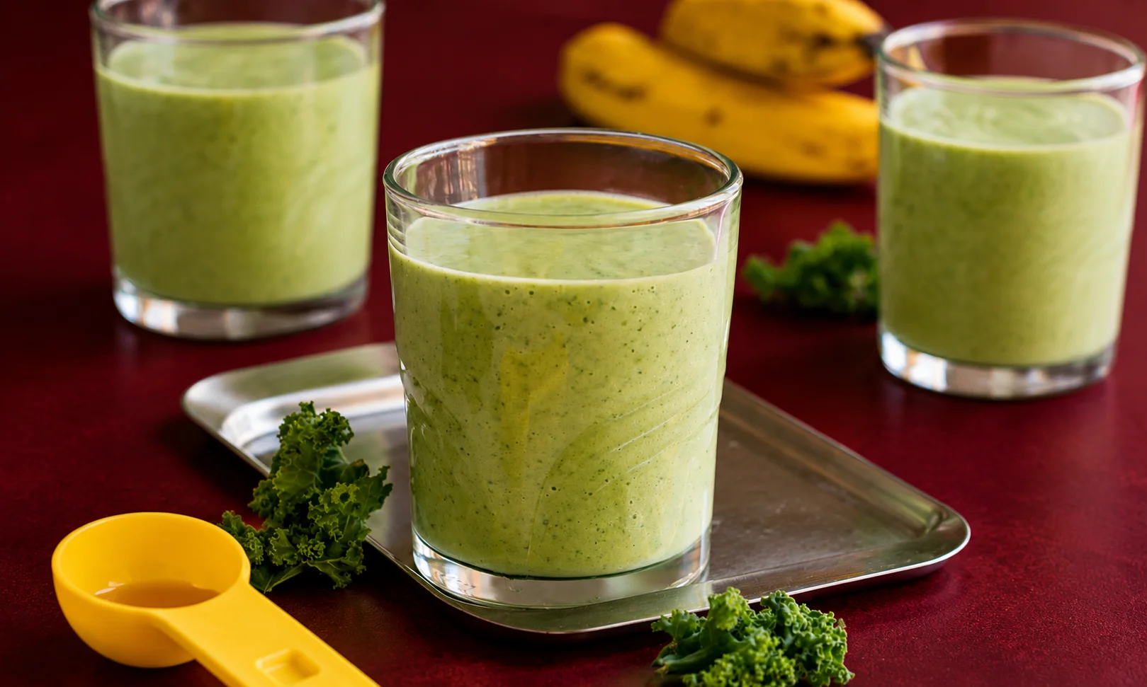 Glasses of green healthy drink on a red surface