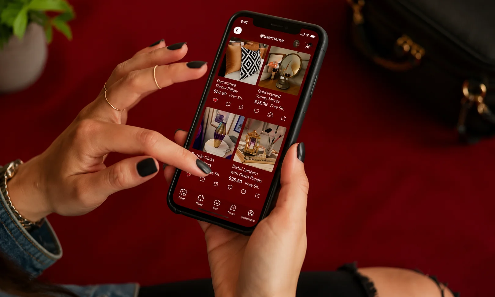 Hands using a mobile phone displaying the Poshmark app in a red-lit setting
