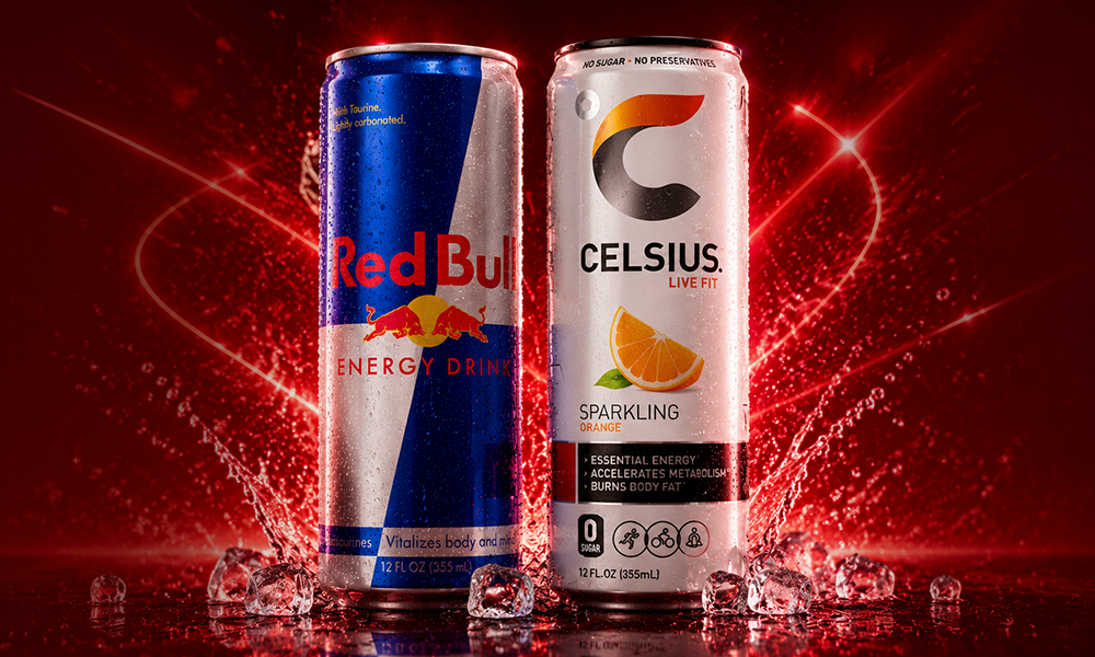 A can of Celsius Cream Soda and a can of Red Bull Ginger Lemon side by side on a premium red pedestal setup