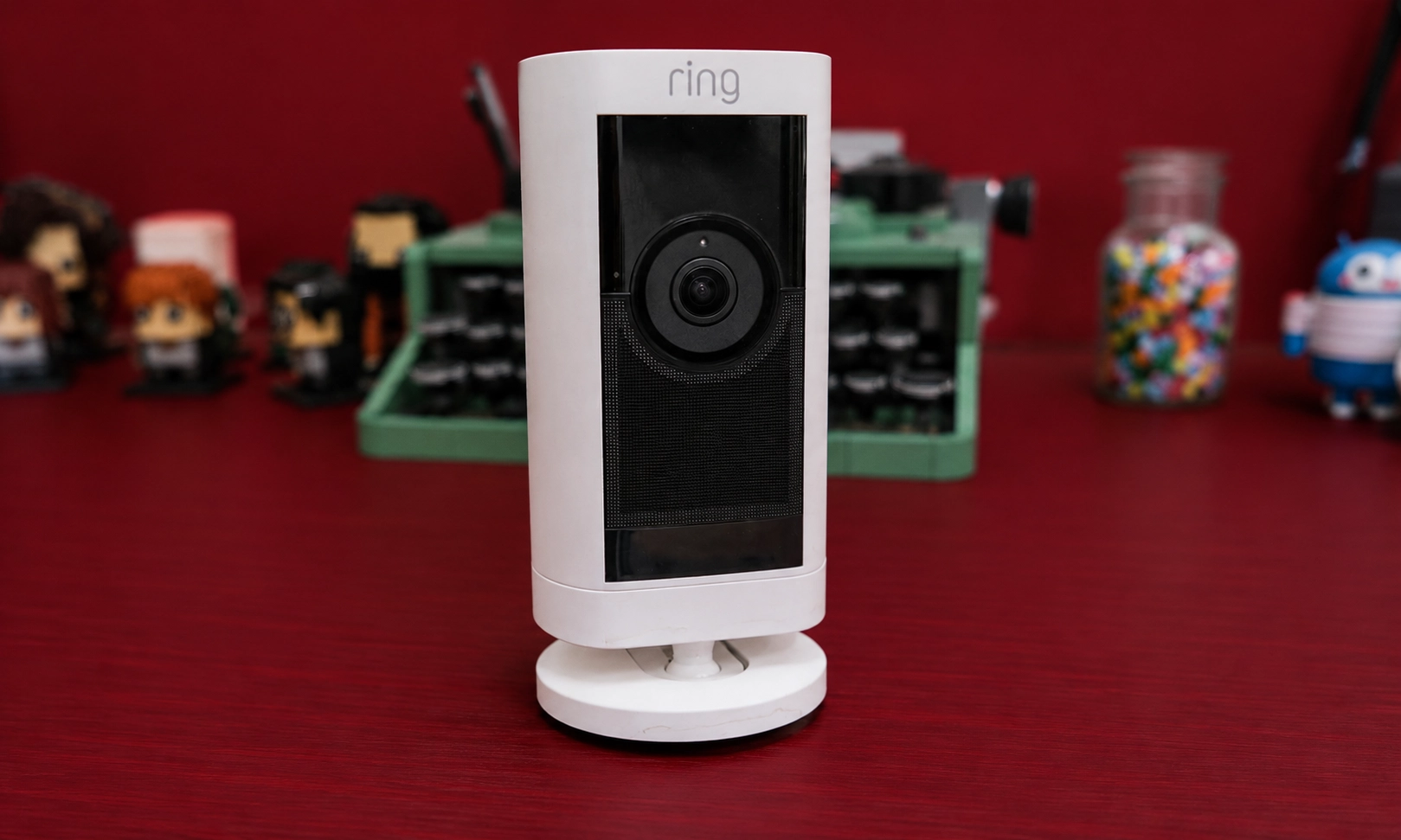 A white indoor security camera standing upright on a dark surface.