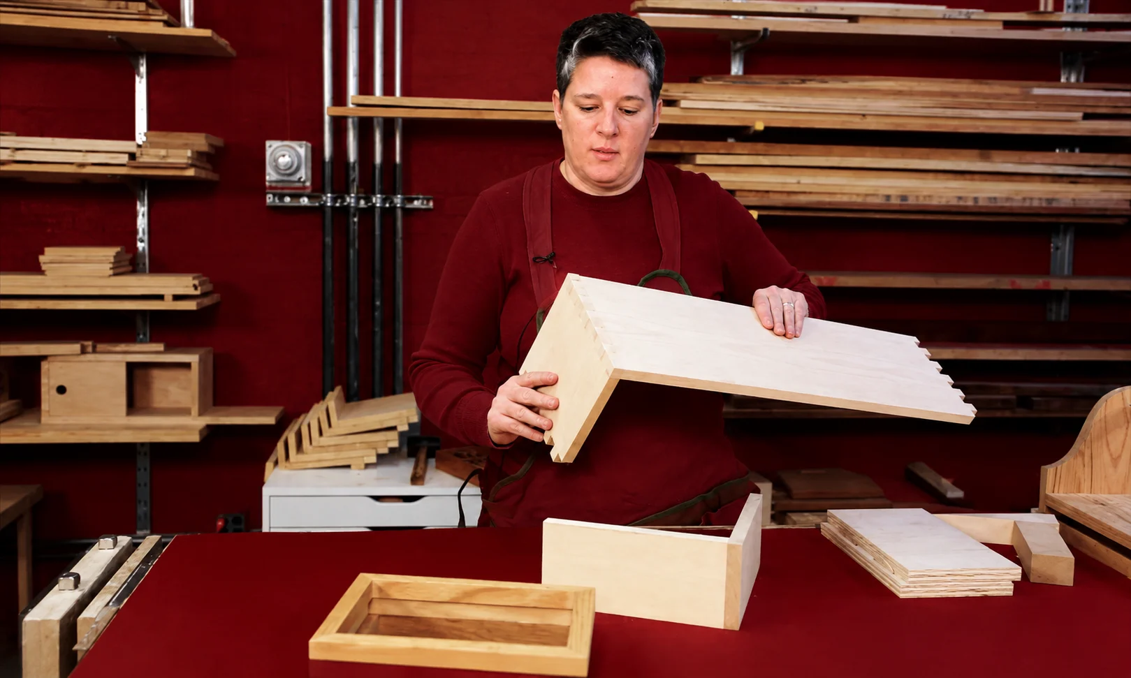 best hobbies for men to make money: Craftsman working on a detailed woodworking project in a workshop with red ambient lighting
