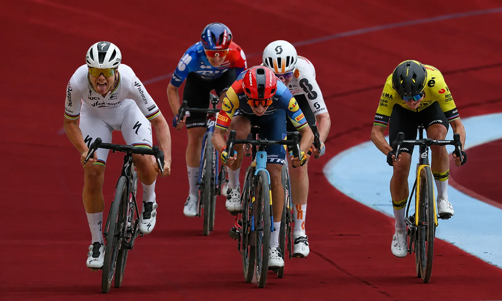 Group of cyclists racing competitively on a professional track under red ambient lighting