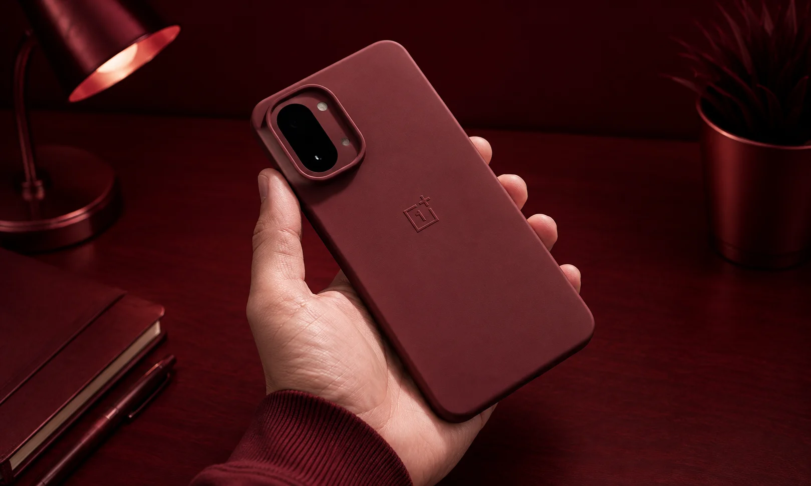 A red-backed OnePlus 15R smartphone held against a dark studio background.