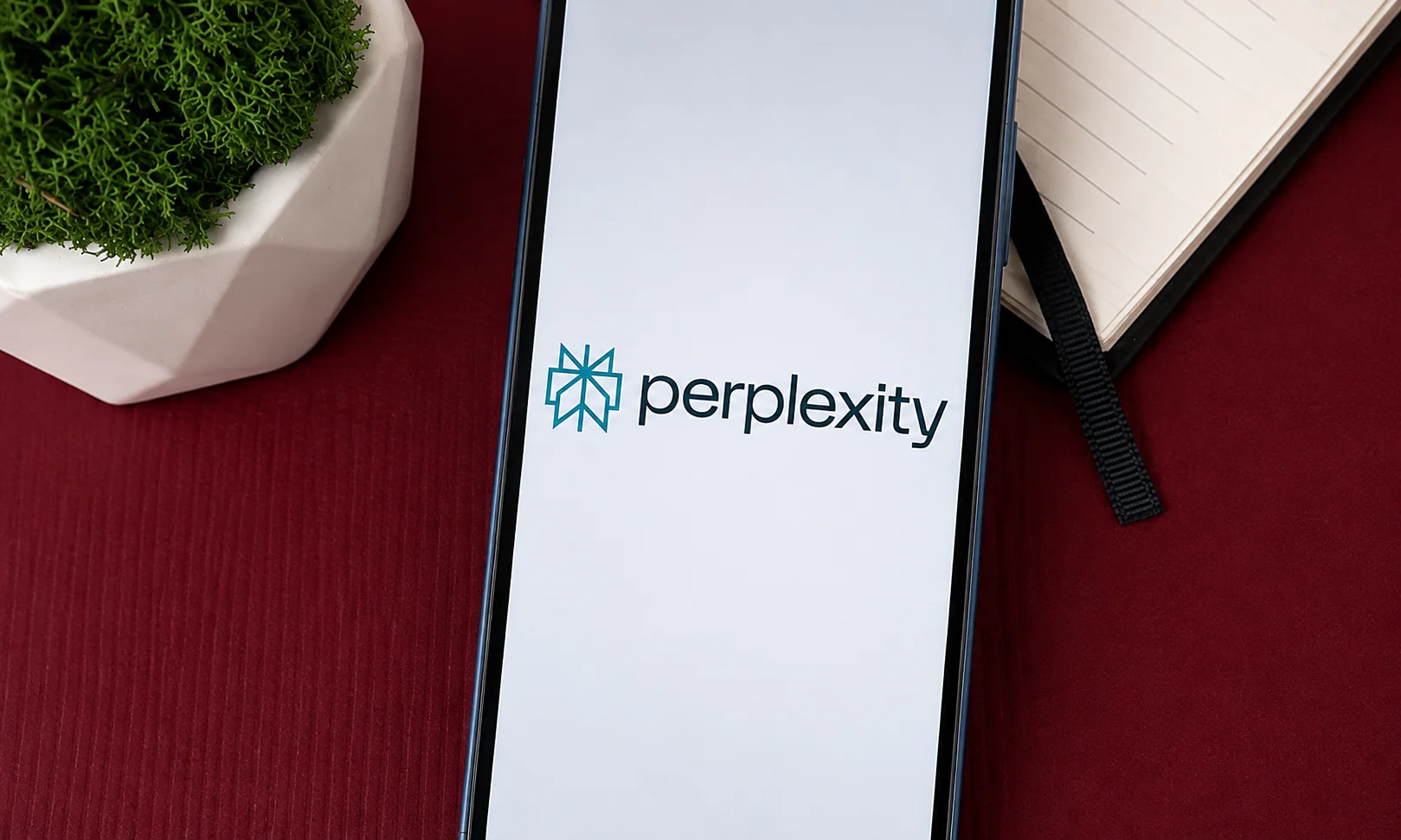 Perplexity AI search interface open on a laptop screen with rich red ambient tones