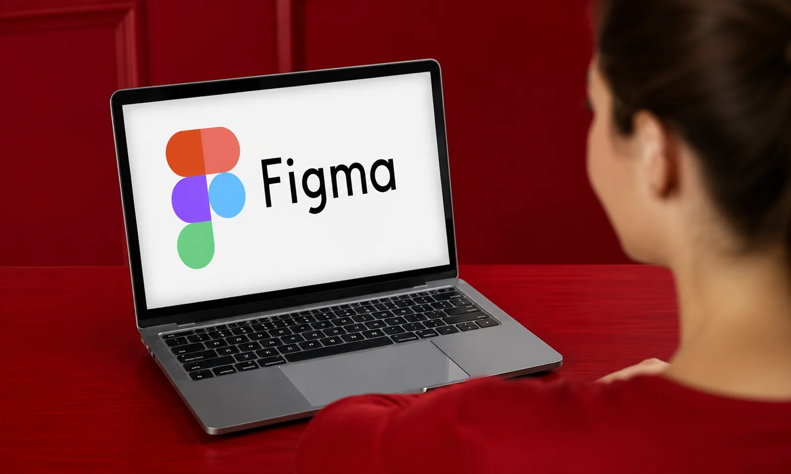 Figma interface open on a laptop screen viewed by a user against a red ambient background