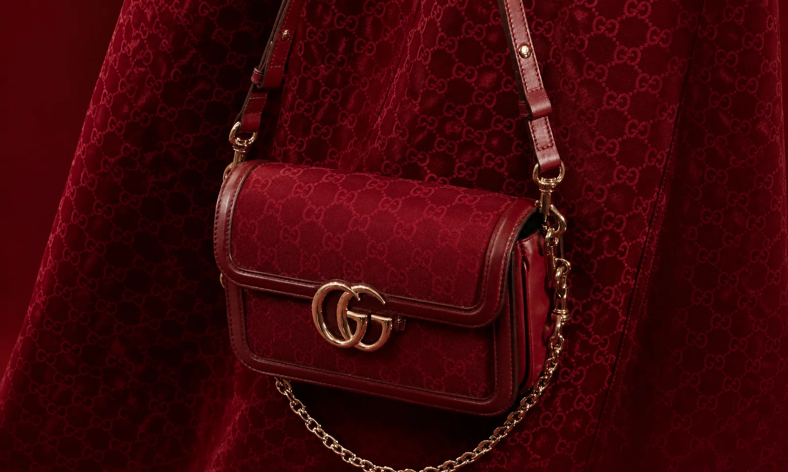A Gucci handbag displayed on a dark red setting.