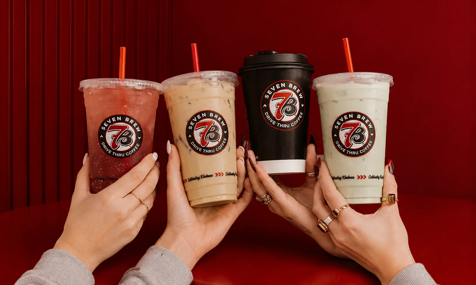 Several branded 7 Brew Coffee cups held up together against a dark background.