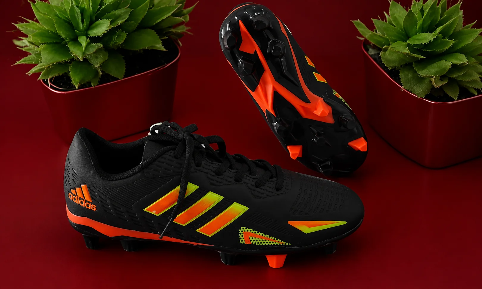 Adidas athletic shoes and packaging on a dark red surface.