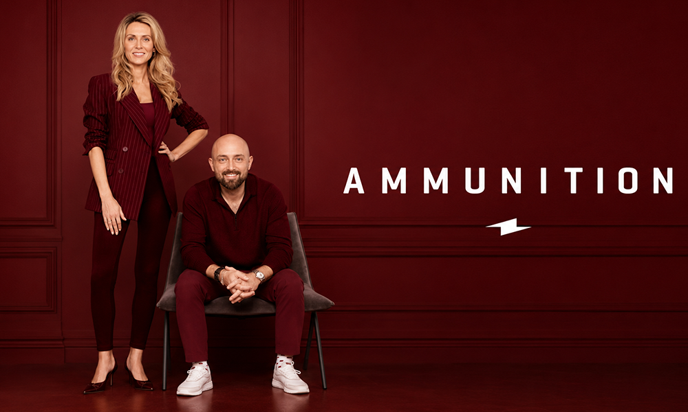 Two people posing together in matching outfits against a professional dark red studio backdrop