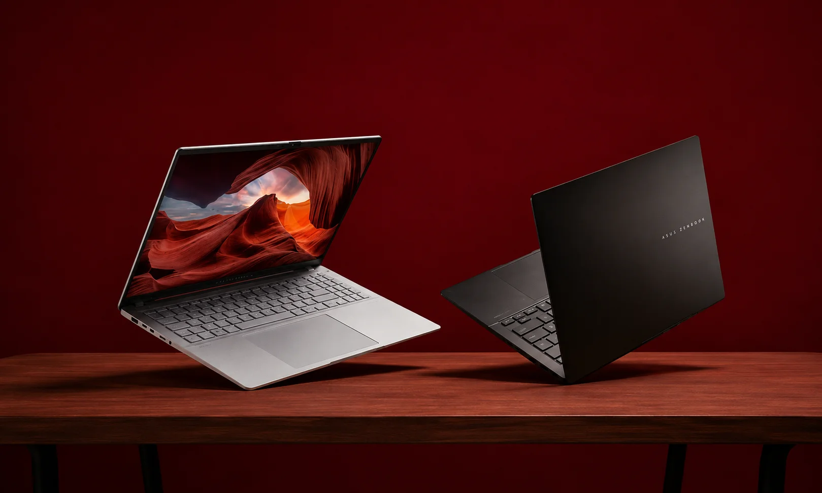 Two sleek laptops displayed against a dark red background to showcase design evolution