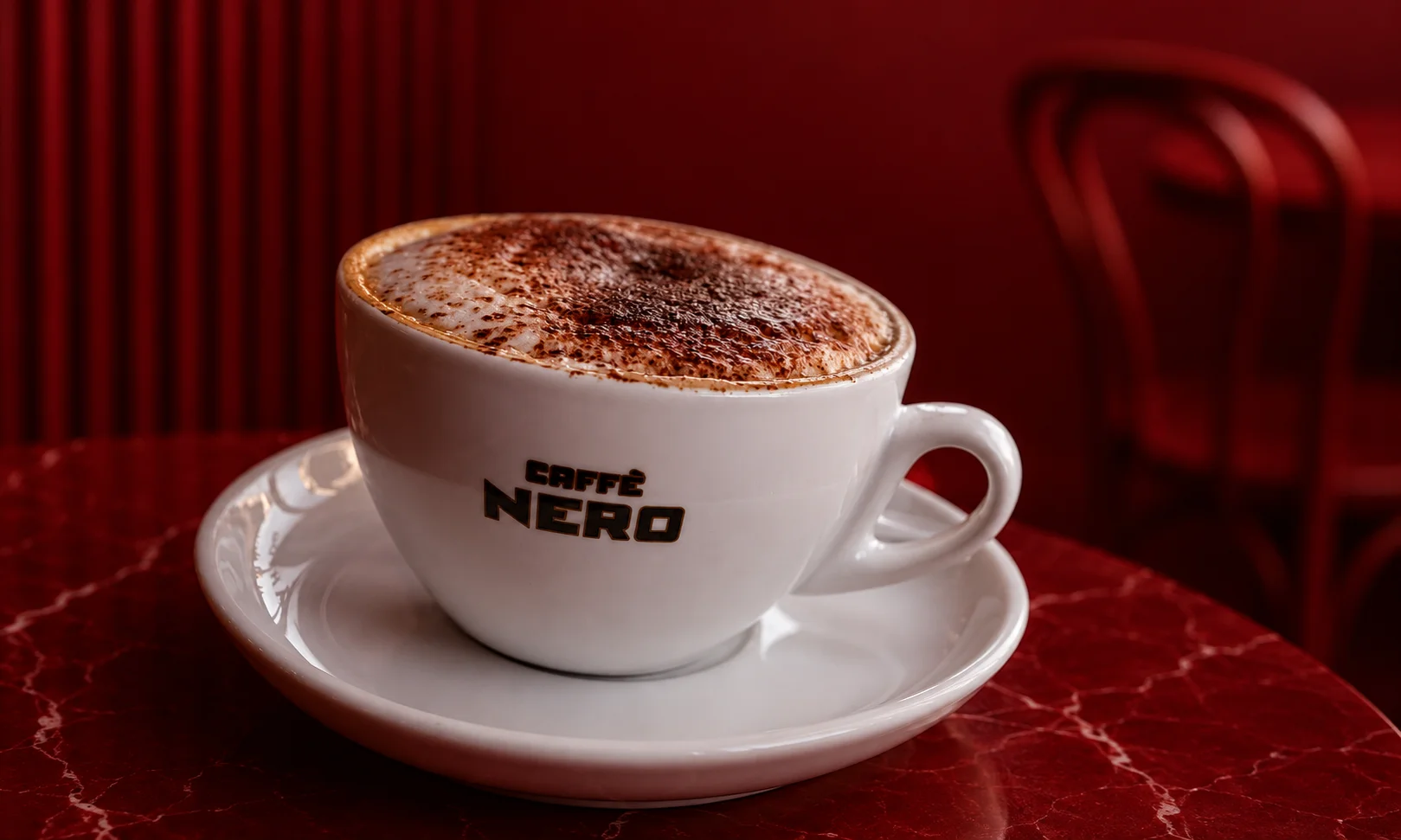 A ceramic cup featuring the Caff&egrave; Nero logo filled with coffee.