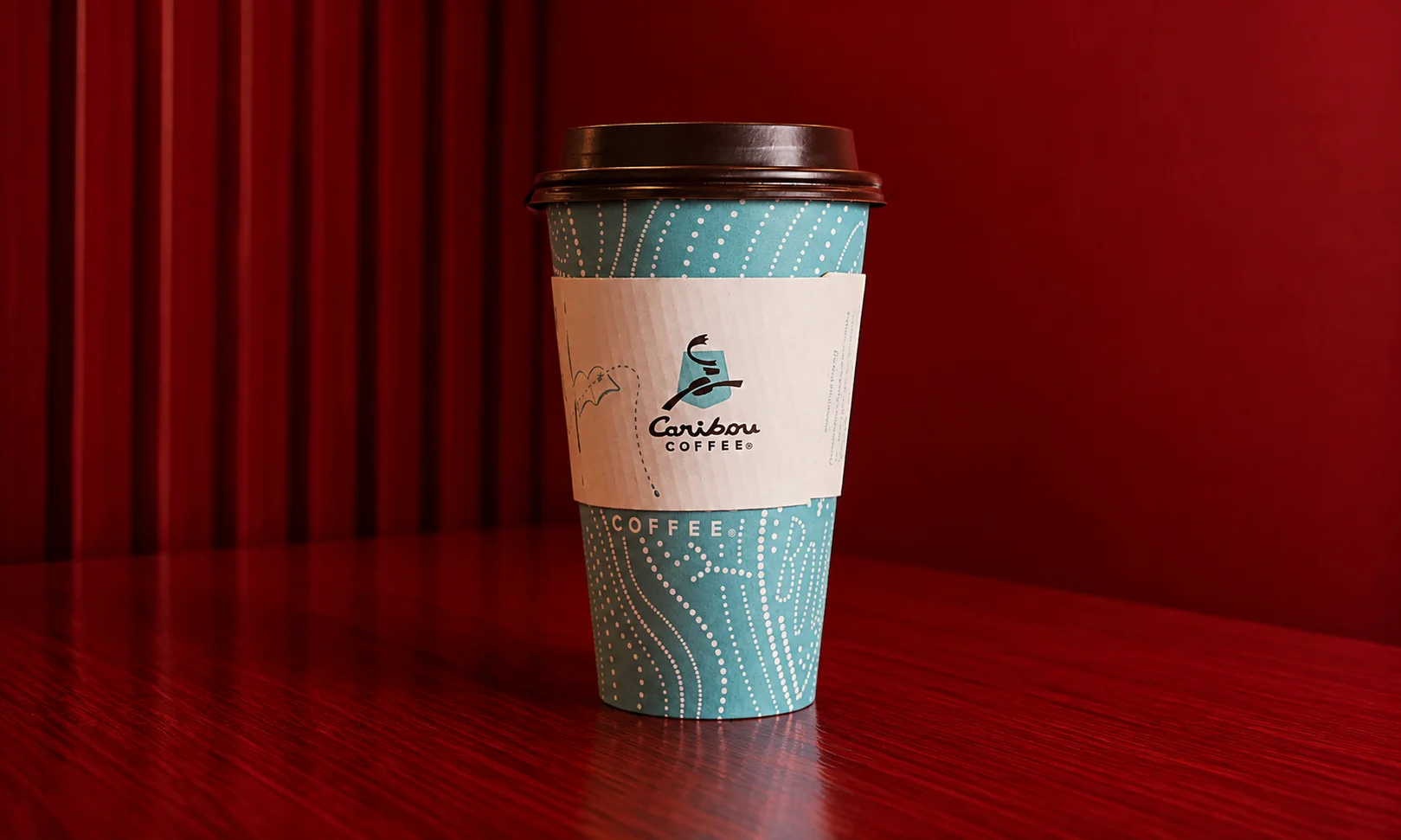 A Caribou Coffee branded cup set against a minimal red and white backdrop.