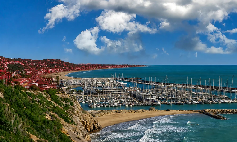 Wide and long sandy shoreline of Castelldefels beach with space for sunbathing and water sports near Barcelona.