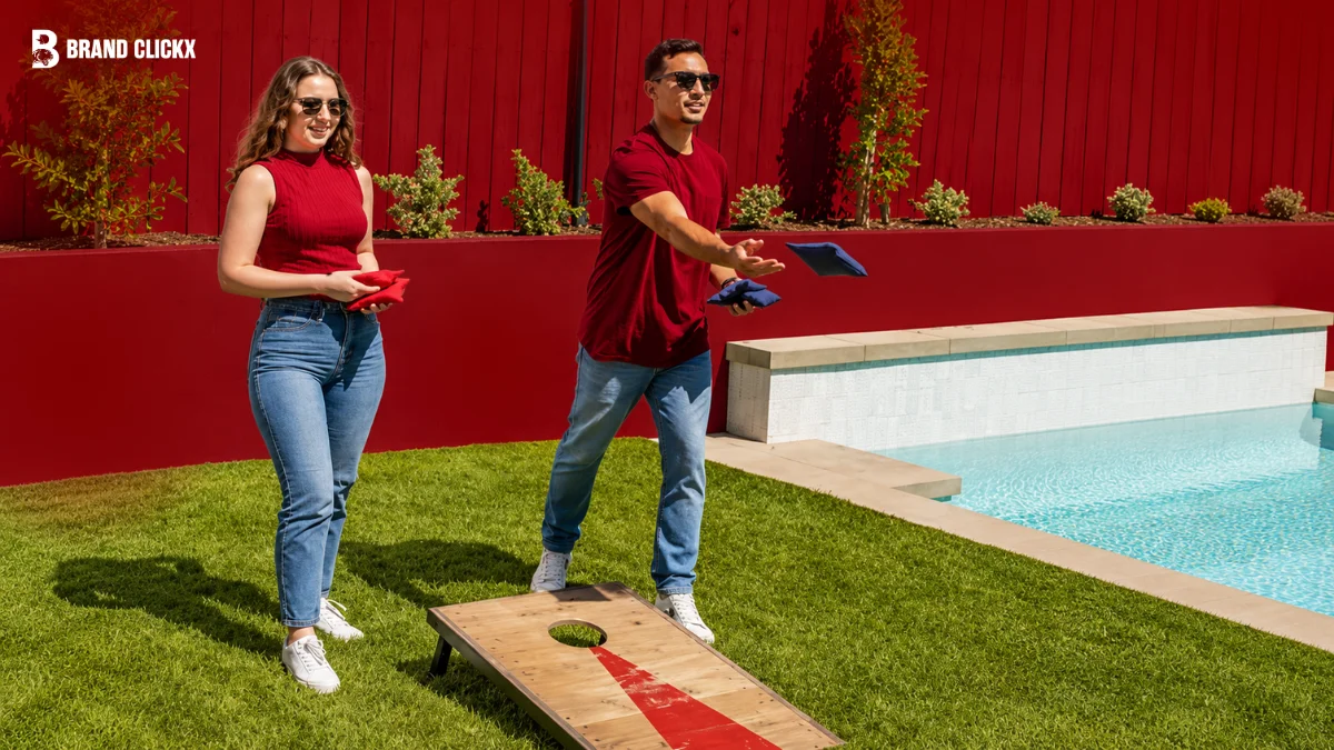 Two wooden cornhole boards set up outdoors on grass facing each other with red and blue throwing bags.