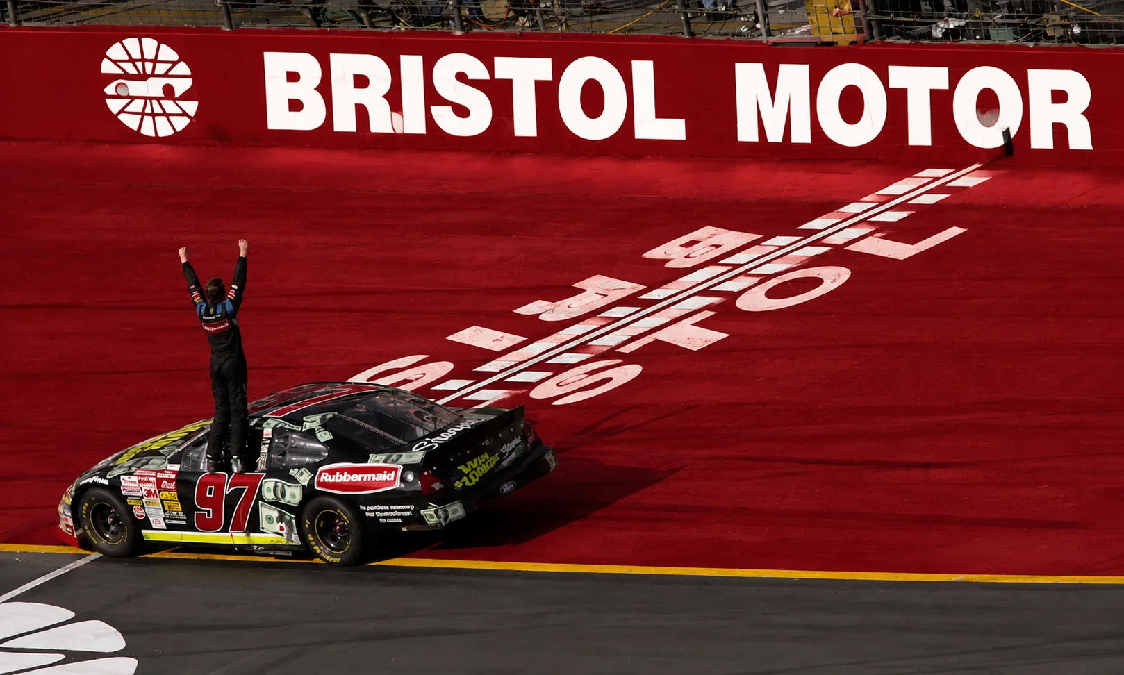 A NASCAR stock car racing on a track under a warm red-toned aesthetic.