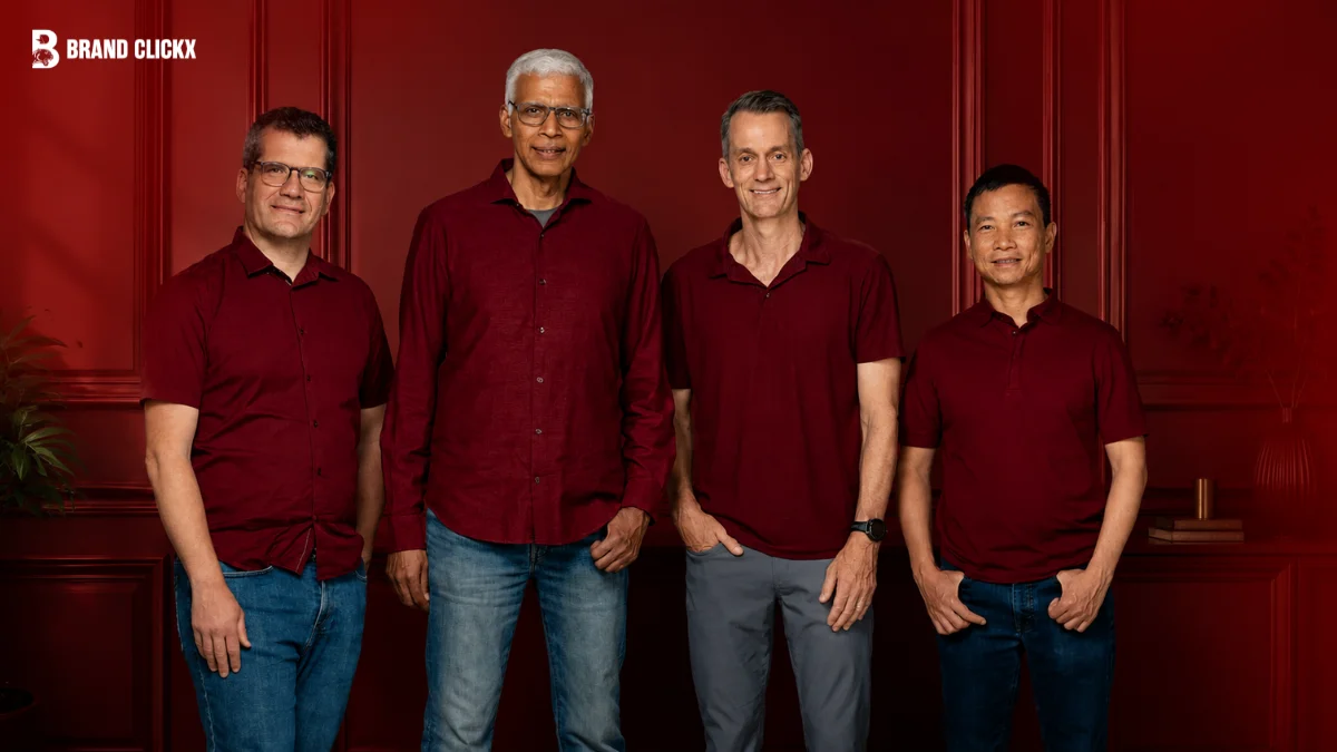Four professional men standing together in matching maroon tops against a rich dark red studio background, featuring the Brand Clickx logo in the top left corner.