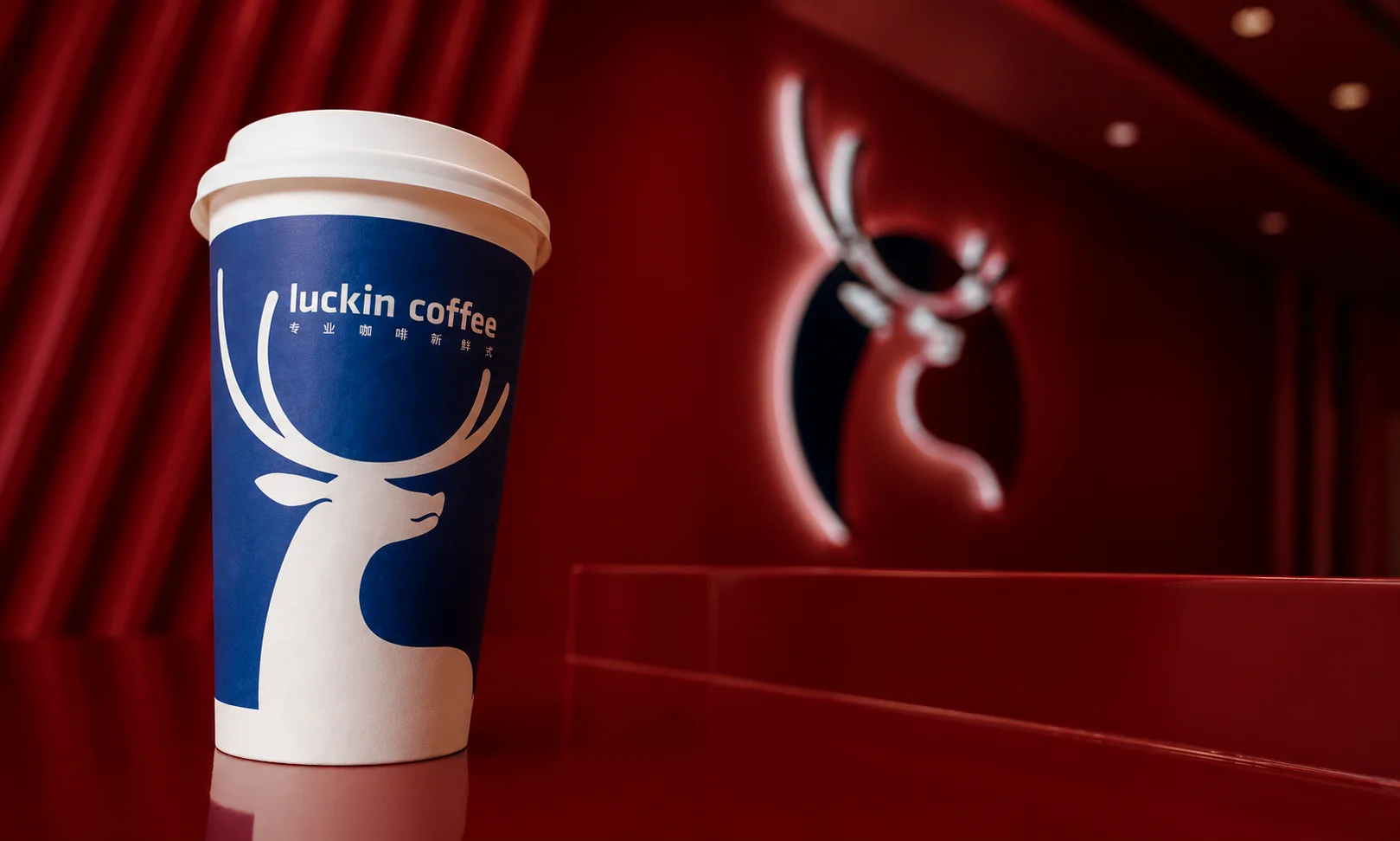 A Luckin Coffee blue and white cup shown in a sleek modern setting.