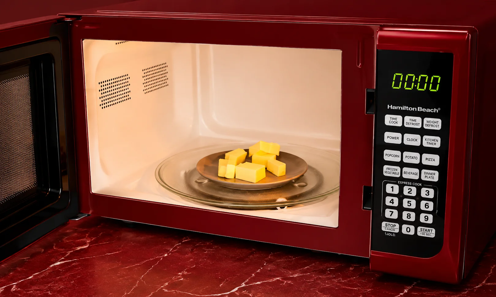 A red microwave containing a small bowl with butter melting inside, set against a dark red ambient background.