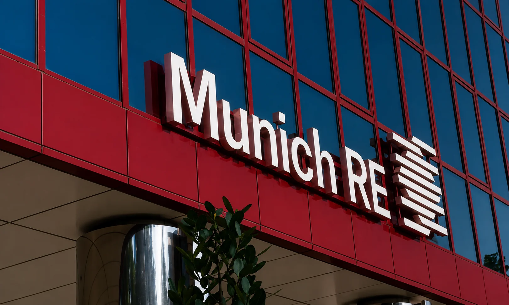 | Best Insurance Companies in the World in 2026 The Munich Re reinsurance company sign mounted on the red exterior facade of a modern corporate building.