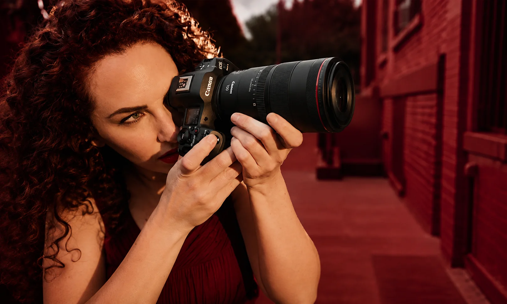 Photographer looking through the viewfinder of a mirrorless camera outdoors