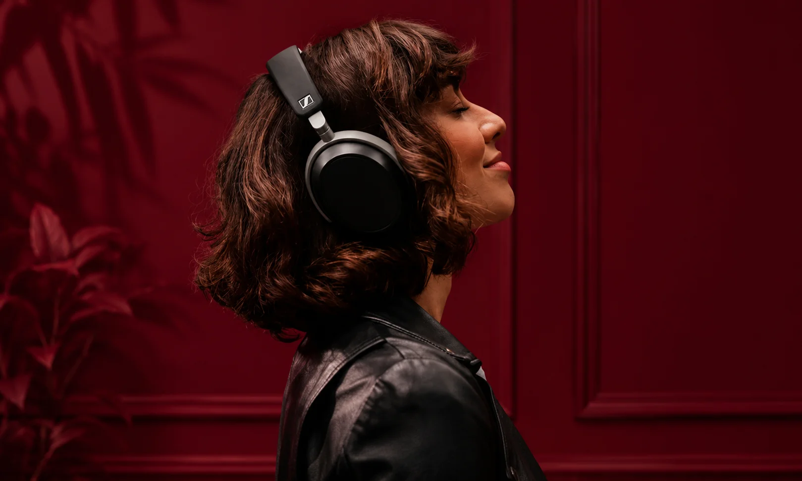 A person wearing Sennheiser headphones against a dark red background.