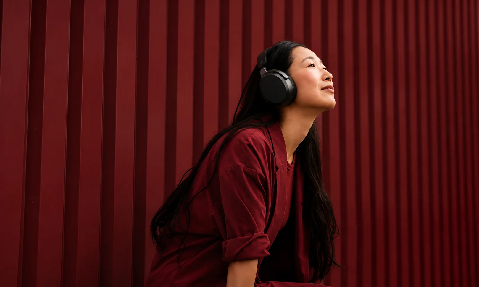A model wearing Sennheiser Momentum 4 headphones in a stylish room setup.