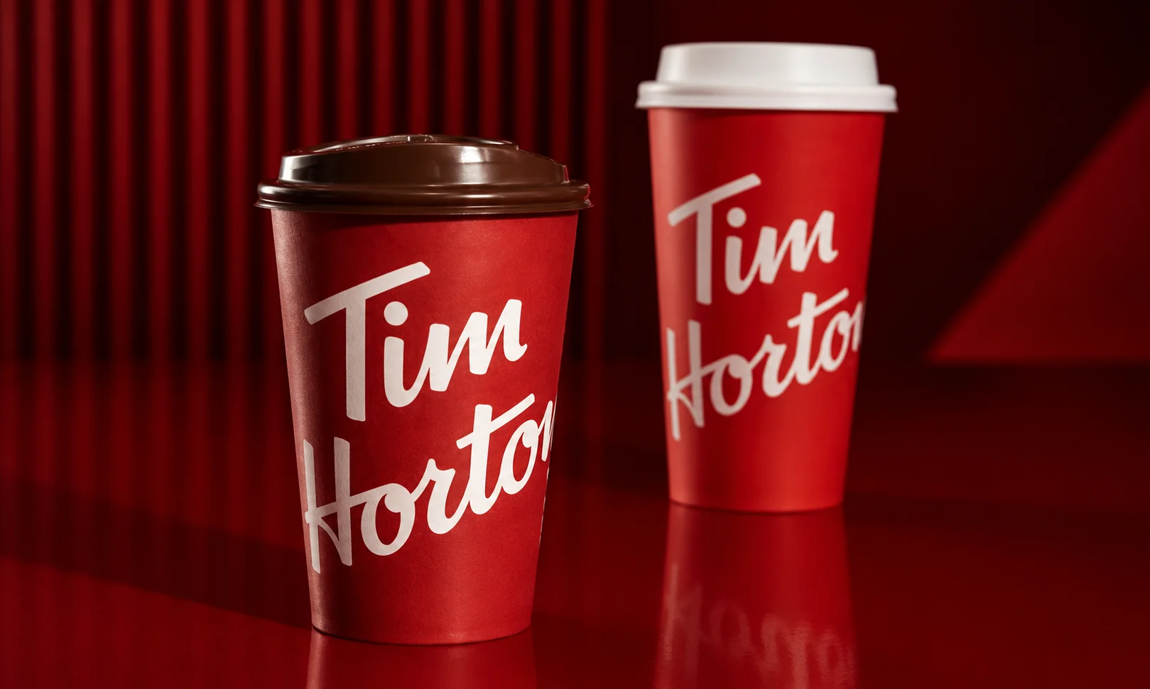Red Tim Hortons branded coffee cups lined up against a matching background.