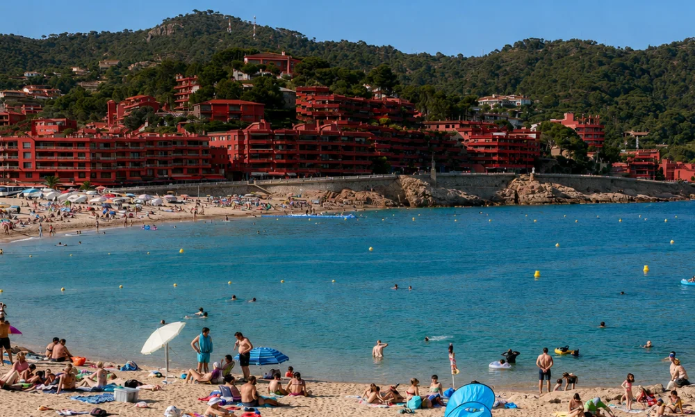 Picturesque Platja Gran beach in Tossa de Mar featuring clear blue water and the ancient walled medieval old town in the background.